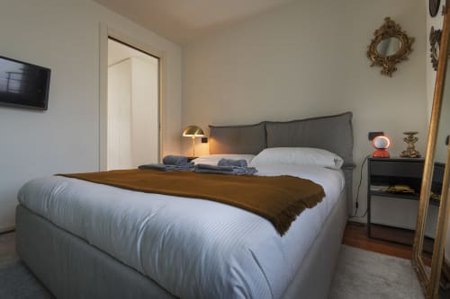Camera moderna della GIRESIO 41 B&B a Milano con biancheria bianca, testata grigia e illuminazione calda