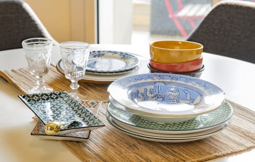 Elegante mise en place al GIRESIO 41 Milano con piatti blu e bianchi, stoviglie impilate, bicchieri d'acqua e dettagli decorativi