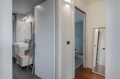 Moderno corridoio del bagno presso il GIRESIO 41 B&B Milano con lavabo bianco, specchio e pavimentazione in legno