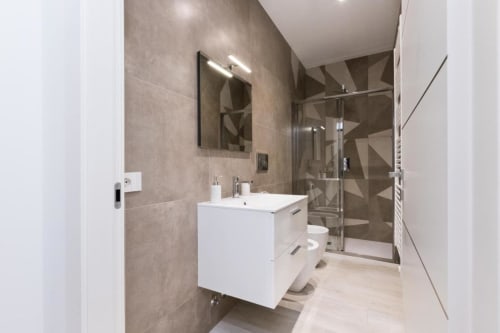 Современная ванная комната в Magnolia Apartments Milan с белой тумбой, геометрической плиткой и стеклянной душевой кабиной