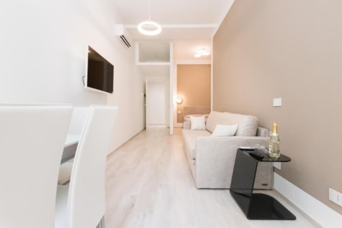 Modernes Wohnzimmer in der Magnolia Apartments Milan mit Sofa, Flachbildfernseher, Kochnische und hellem Holzboden