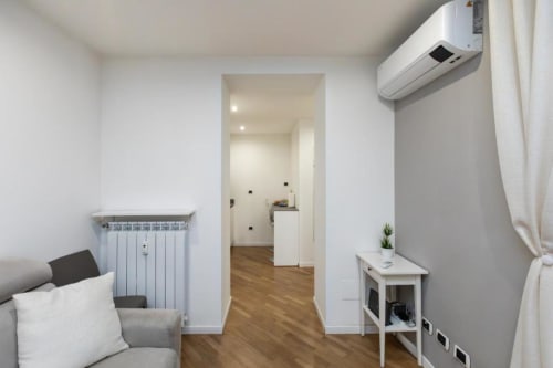 Modernes Studio-Apartment in Mailand mit Wohnbereich, Heizkörper, Klimaanlage und Flur zur Kochnische