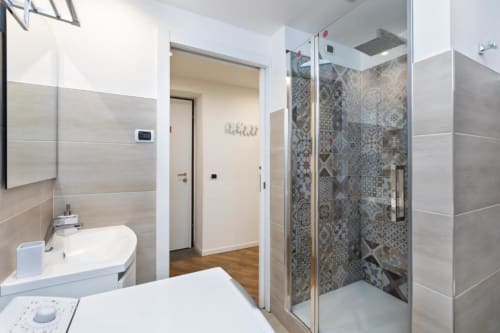 Modernes Badezimmer in den Magnolia Apartments Mailand mit Waschbecken, Toilette und begehbarer Dusche mit dekorativen Fliesen