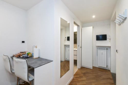 Moderner Flur in den Magnolia Apartments Mailand mit Küchenbereich, weißen Wänden, Holzböden und moderner Einrichtung