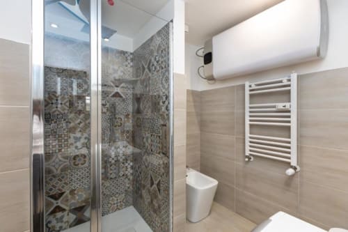 Modernes Badezimmer im Magnolia Apartments Milan mit gemustertem Duschbelag, weißem Heizkörper und neutraler Einrichtung