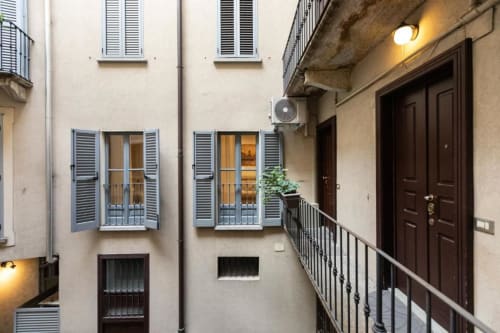 Innenhof der Magnolia Apartments Mailand mit Läden, Balkonen und Holztüren in historischem Gebäude
