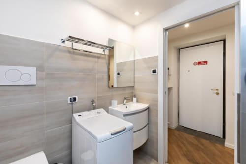Modernes Badezimmer in der Magnolia Apartments Mailand mit Dusche, Waschbecken, Waschmaschine und Holzboden