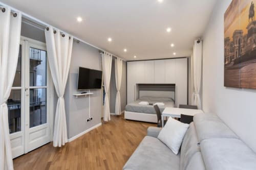 Современная спальня в отеле Magnolia Apartments Milan с диваном, кроватью, ТВ и дверями на балкон