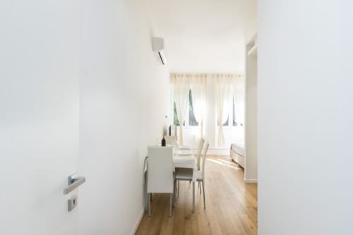 Moderner Essbereich in Magnolia Apartments Mailand Zimmer 18B mit weißen Wänden, Holzparkett und reichlich Tageslicht