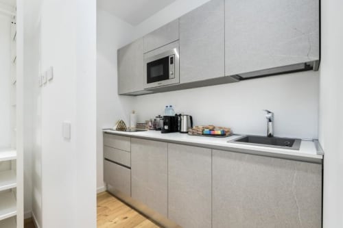 Moderne Kochnische in der Magnolia Apartments Mailand mit Edelstahlgeräten, Mikrowelle, Spüle und Holzboden