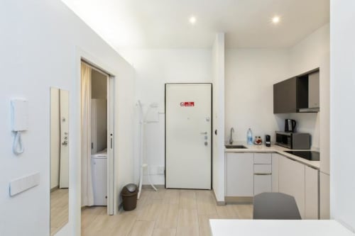 Moderne Küchenzeile in Magnolia Apartments Milan mit weißen Schränken, Geräten und Badezimmereingang