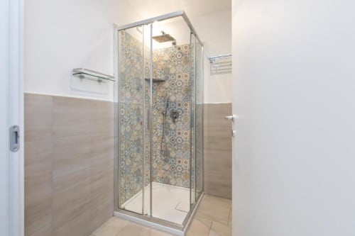 Modernes Glassduschenclosure mit dekorativem Fliesenwandbelag im Badezimmer von Magnolia Apartments Mailand
