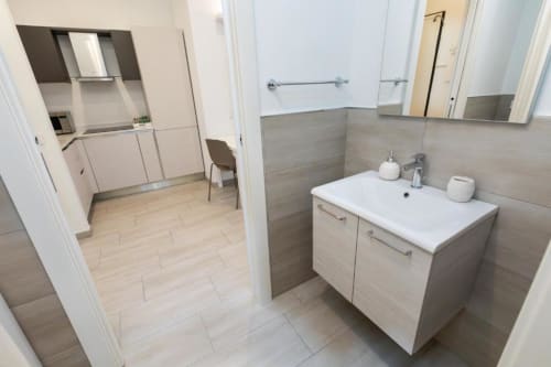 Modernes Badezimmer mit Waschbecken und grauen Fliesenwänden in den Magnolia Apartments Milan, Lage mit Stadtblick