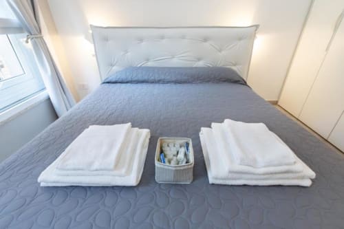 Weiße Handtücher und Toilettenartikel ordentlich auf dem Bett im Magnolia Apartments Mailand Hotelzimmer mit Stadtblick arrangiert