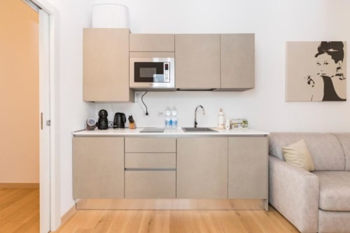 Moderne Kochnische in Mailänder Wohnung mit beigen Schränken, Mikrowelle, Spülbecken und nahegelegenem Sofa