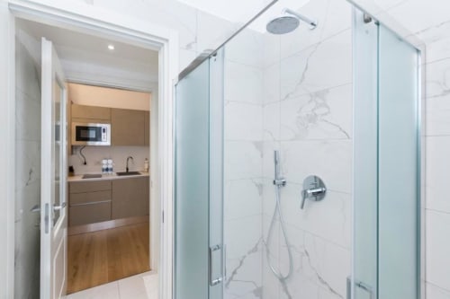 Modernes Badezimmer mit Marmor-Dusche in den Magnolia Apartments Mailand, verbunden mit dem Küchenbereich