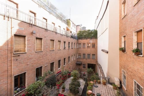 Innenhof der Magnolia Apartments Mailand mit Backsteingebäuden, Topfpflanzen und Gartenbereich zum Entspannen