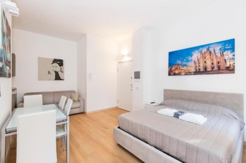 Modernes Studio-Apartment in den Magnolia Apartments Mailand mit Bett, Sofa, Kochnische und Kunstwerk des Mailänder Doms.