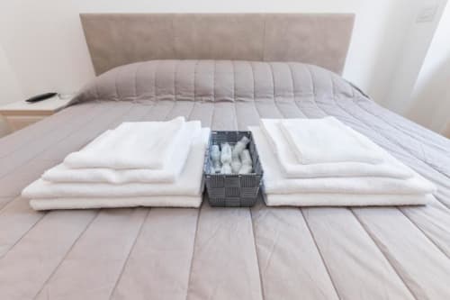 Ordentlich arrangierte weiße Handtücher und Utensilien auf dem Bett im Hotelzimmer von Magnolia Apartments Milan