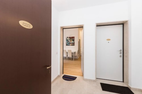 Moderner Eingangsbereich des Magnolia Apartments Mailand mit brauner Akzentwand, weißen Türen und Parkettboden