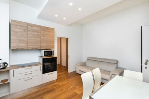 Modernes Apartment mit offener Grundfläche in den Magnolia Apartments Mailand mit ausgestatteter Küche, Sofa, Essbereich und Holzboden