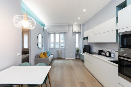 Moderne offene Küche und Wohnzimmer in Mailänder Apartment mit weißen Möbeln, Holzfußboden und Stadtblick