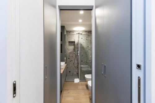 Modernes Badezimmer mit Glaskabine in den Magnolia Apartments Milan, weiße Wände und Holzboden
