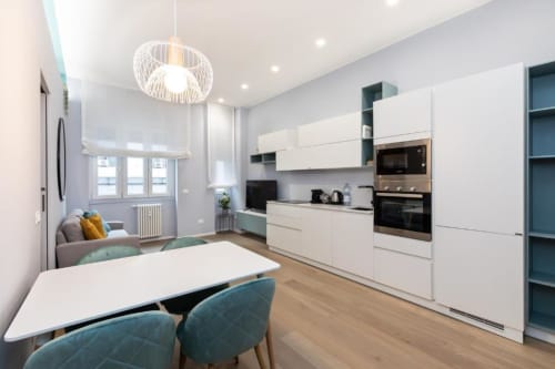 Moderne Küche und Essbereich in den Magnolia Apartments Mailand mit weißen Schränken, Edelstahlgeräten und Stadtblick