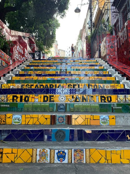 Escada com azulejos coloridos no Rio de Janeiro com padrões geométricos amarelos, azuis e verdes no Rio Vibes Hostel