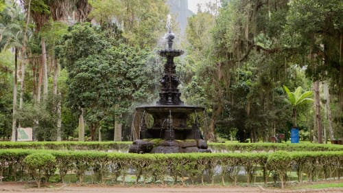 Fonte ornamental cercada por vegetação exuberante e árvores altas em um parque do Rio de Janeiro