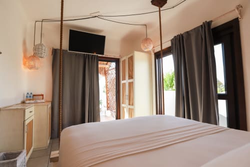 Habitación moderna del Hotel 40 Cañones en Mahahual con cama, lámparas colgantes, cortinas oscuras y puertas con vista al océano