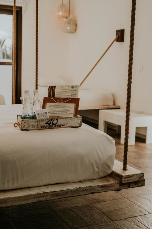 Dormitorio minimalista del Hotel 40 Cañones en Mahahual con cama suspendida, detalles de cuerda y vista al patio