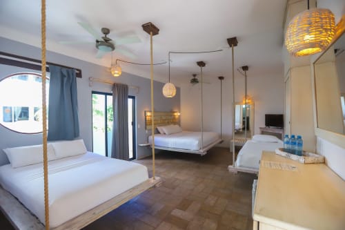 Habitación del Hotel 40 Cañones en Mahahual con camas de cuerdas, iluminación colgante y comodidades modernas