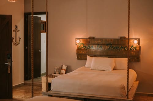 Habitación con temática náutica en el hotel 40 Cañones de Mahahual, con cama suspendida por cuerdas e iluminación cálida