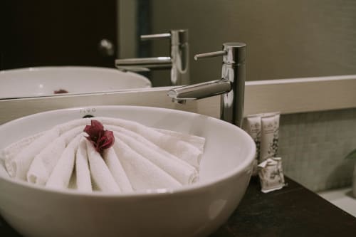 Elegante lavamanos del Hotel 40 Cañones con toalla blanca doblada y flor roja como detalle decorativo