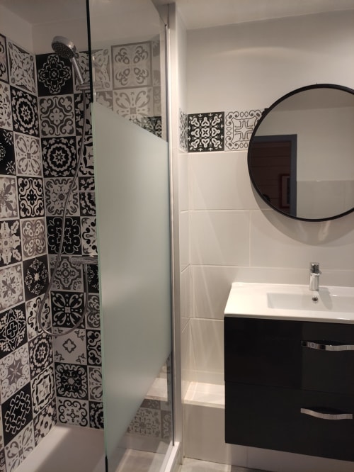 Modern bathroom at Le Pavillon Saint Martin Hotel in Souillac with black and white patterned tiles, round mirror, and black