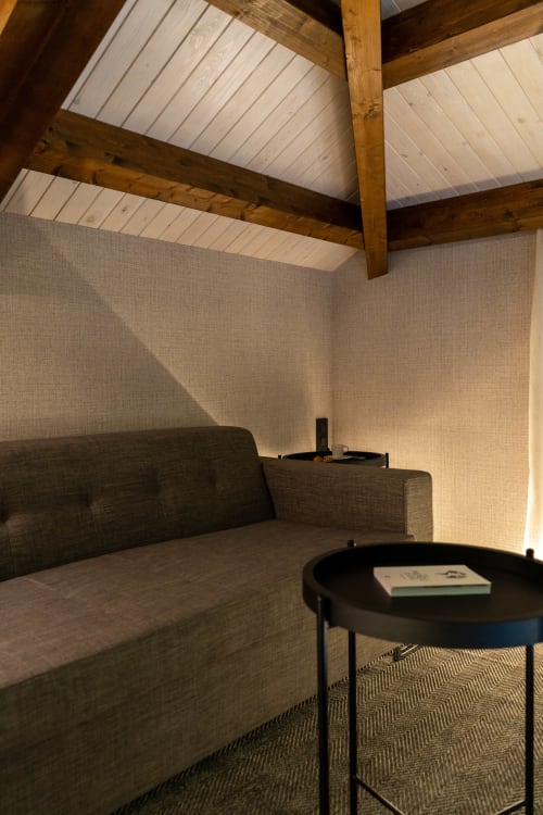 Acogedor rincón dormitorio en Casa Rural San Andres de Teixido con vigas vistas, asientos tapizados y mesita redonda