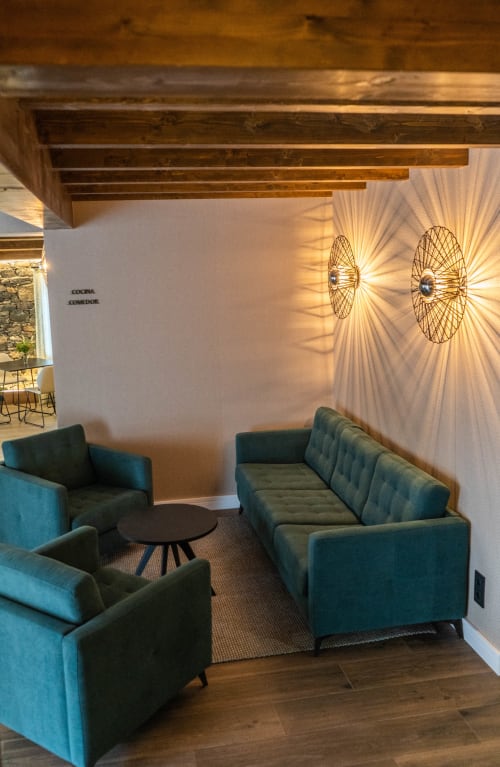Acogedora sala de estar en Casa Rural San Andres de Teixido con asientos color azul verdoso, vigas de madera y luminarias decorativas