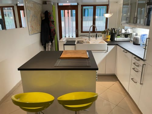 Cuisine moderne de l'appartement Chez Adrien Paris avec tabourets jaunes, îlot noir et vue sur la ville