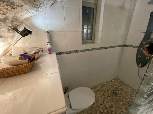 Salle de bains moderne de l'appartement Chez Adrien Paris avec carrelage blanc, frise mosaïque, toilettes et douche