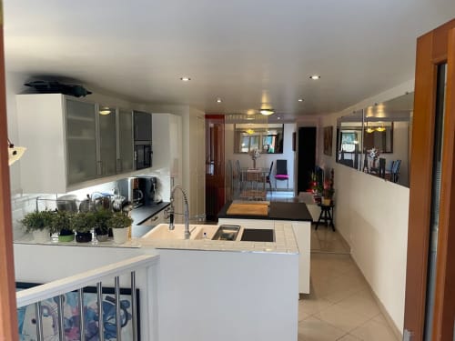 Cuisine ouverte et séjour modernes dans un appartement parisien avec armoires blanches, appareils inox et vue sur la ville
