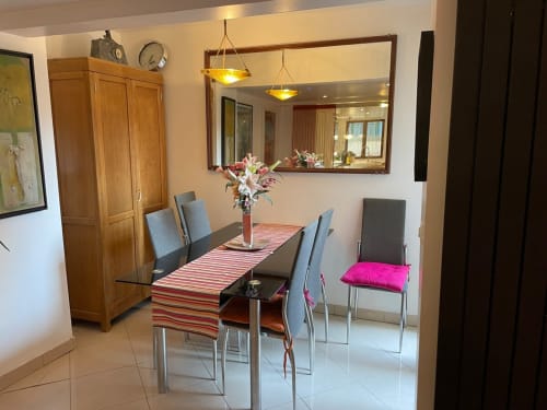 Salle à manger moderne au Chez Adrien Paris avec chemin de table rayé, chaises grises rembourrées, meuble en bois