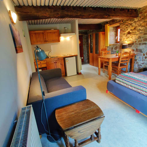 Studioappartement in La Ferme De Werpin met keuken, zithoek, bedden, houten balken en stenen muren in Hotton