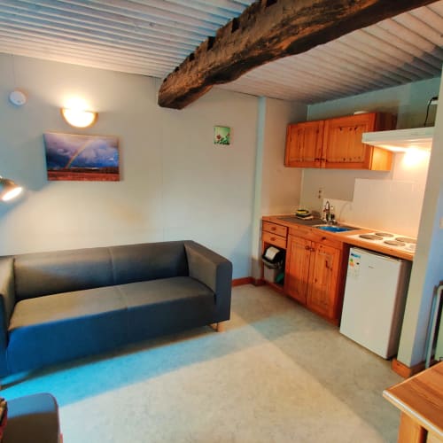 Studioappartement in La Ferme De Werpin in Hotton met keuken, bank en rustiek houten balkenplafond