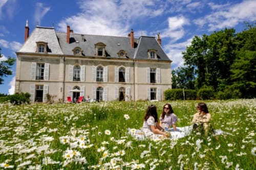 Trois femmes assises dans un champ de marguerites avec le château de Vaux Morvan en arrière-plan, Étang-sur-Arroux