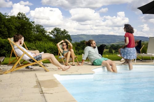 Des invités se détendent au bord de la piscine du Château de Vaux Morvan en Morvan, France, avec vue sur la campagne
