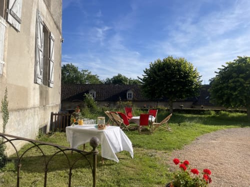 Espace détente du Château de Vaux Morvan avec chaises longues rouges et table blanche à Étang-sur-Arroux