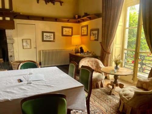 Élégante salle à manger du Château de Vaux Morvan avec fauteuils en velours vert, nappe blanche, art équestre encadré