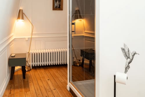 Elegant hotel room at Henri II in Le Mans featuring hardwood floors, brass floor lamp, radiator, and modern bathroom entrance