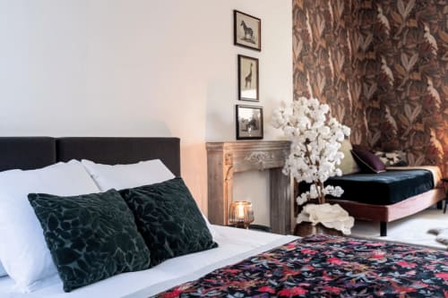 Chambre élégante à l'hôtel Henri II au Mans avec tête de lit foncée, literie blanche et arrangement floral décoratif